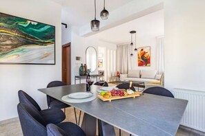 A modern dining area with a dark table, black chairs, and a fruit platter.