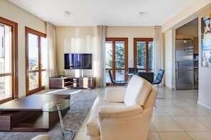 Ein modernes Wohnzimmer mit einer Couch, einem Fernseher und einem Essbereich mit Tisch und Stühlen.