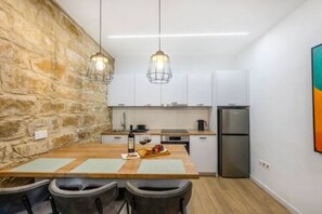 Una cocina moderna con una pared de acento de piedra, luces colgantes y una zona de comedor con sillas y una mesa.