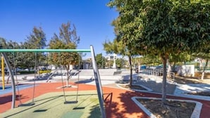 Ein Spielplatz mit Schaukeln und einem umzäunten Bereich.