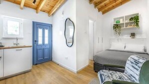 Ein Zimmer mit einem Bett, einer blauen Tür, einem Spiegel und einem Regal mit Pflanzen.