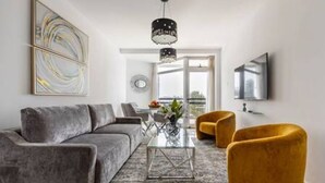 Un salon moderne avec un canapé gris, une table basse en verre et un fauteuil jaune.