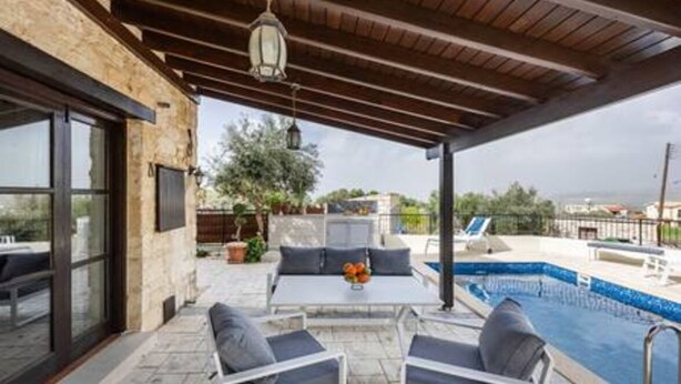 Um pátio externo com piscina, área de estar e vista para o mar.