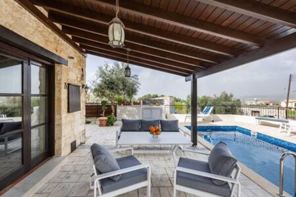 An outdoor patio with a pool, seating area, and a view of the sea. - Stroumpi Private Pool Villa (Stroumpi)