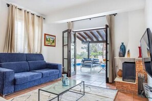 A living room with a sofa, a glass coffee table, a fireplace, and a TV. - Stroumpi Private Pool Villa (Stroumpi)