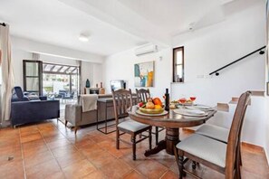 A modern kitchen with a dining table set for two, a sofa, and a staircase. - Stroumpi Private Pool Villa (Stroumpi)