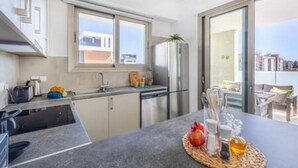 Une cuisine moderne dotée d’un lave-vaisselle intégré, d’une grande fenêtre et d’un coin repas avec une table mise pour deux personnes.