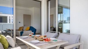 Un balcon avec une table à manger pour deux personnes, un canapé et une vue sur la ville.