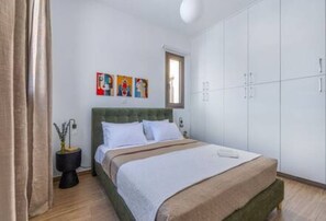 A bedroom with a bed, a wardrobe, and a window. - 101 Mulberry Court - Spacious with Large Terrace (Agios Athanasios)