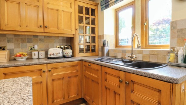 Una cocina con armarios de madera, encimera de granito, ventana con vistas y un fregadero.