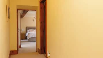 A hallway leading to a bedroom with a bed, a nightstand, and a lamp.