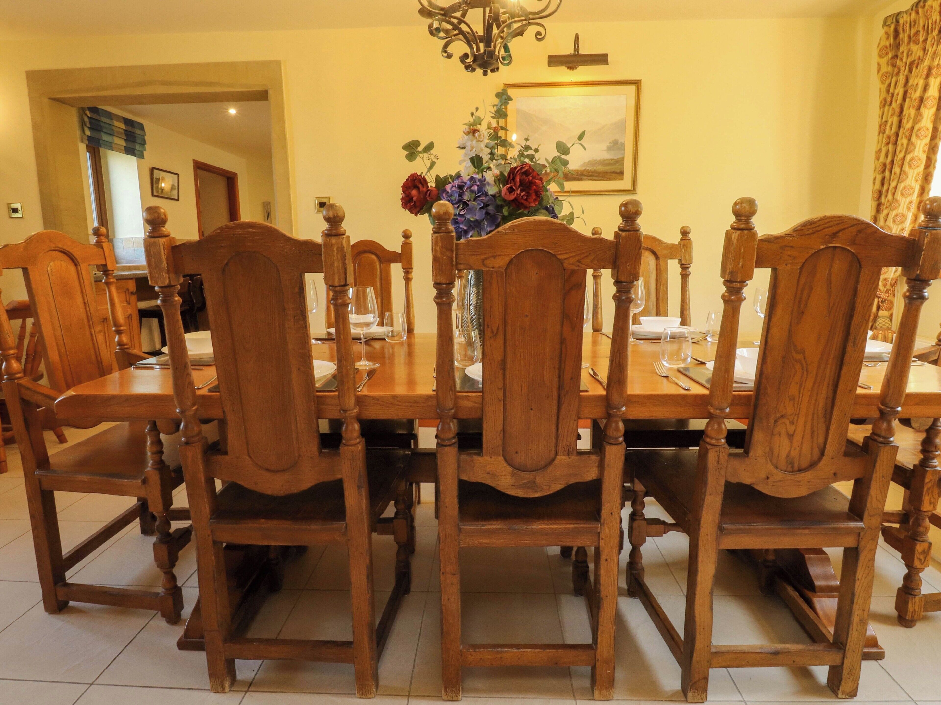A dining area with a wooden table and chairs, a vase of flowers, and a painting on the wall.