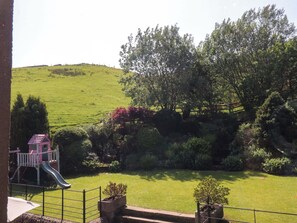 A grassy area with a playground, including a slide, and a hill in the background. - Sheephouse Farm (Bacup)