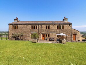 A stone building with a large lawn in front, a door, and a window. - Sheephouse Farm (Bacup)
