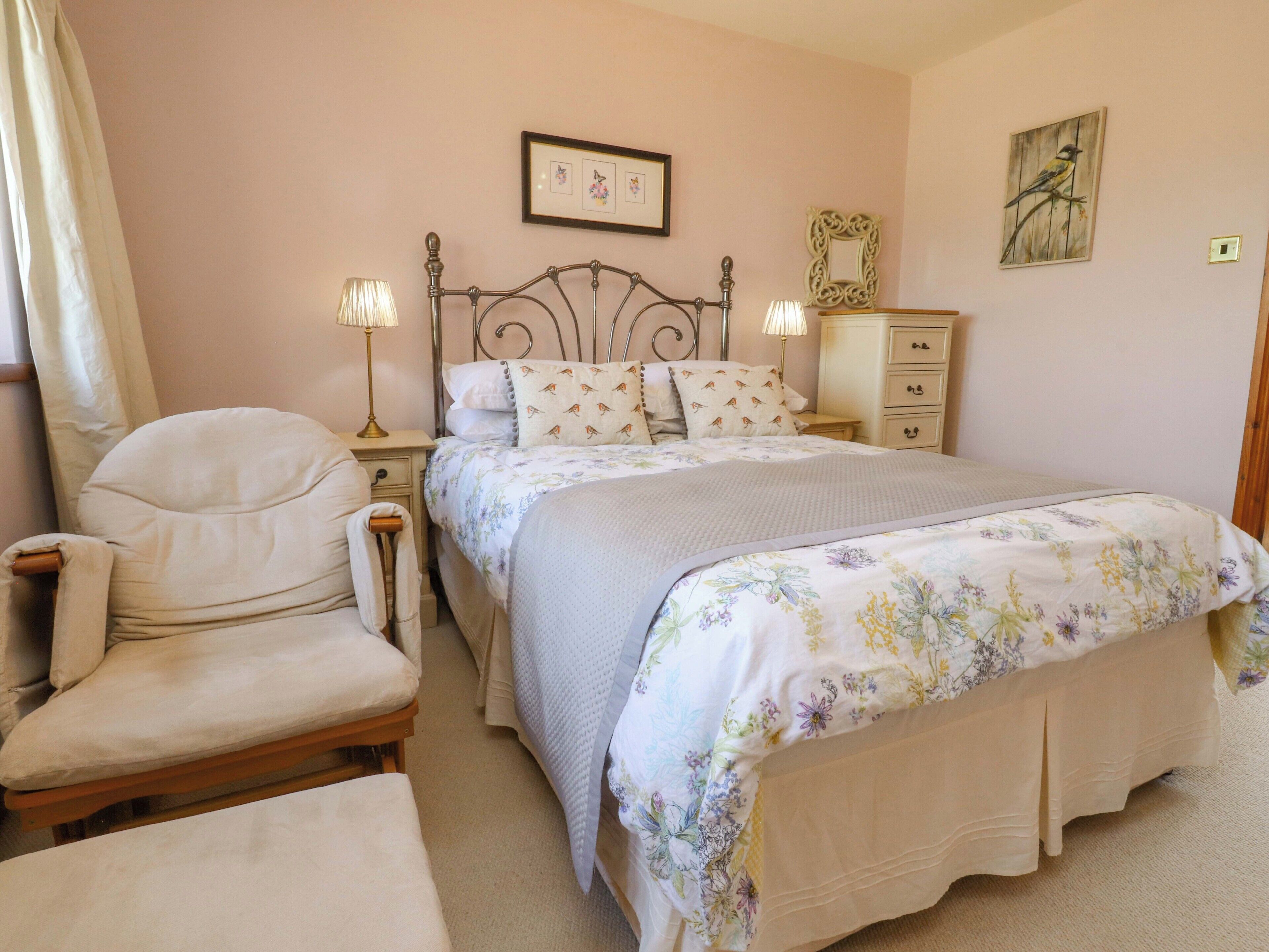 Un dormitorio con cama, una silla, una mesita de noche, un aparador y decoración en la pared.