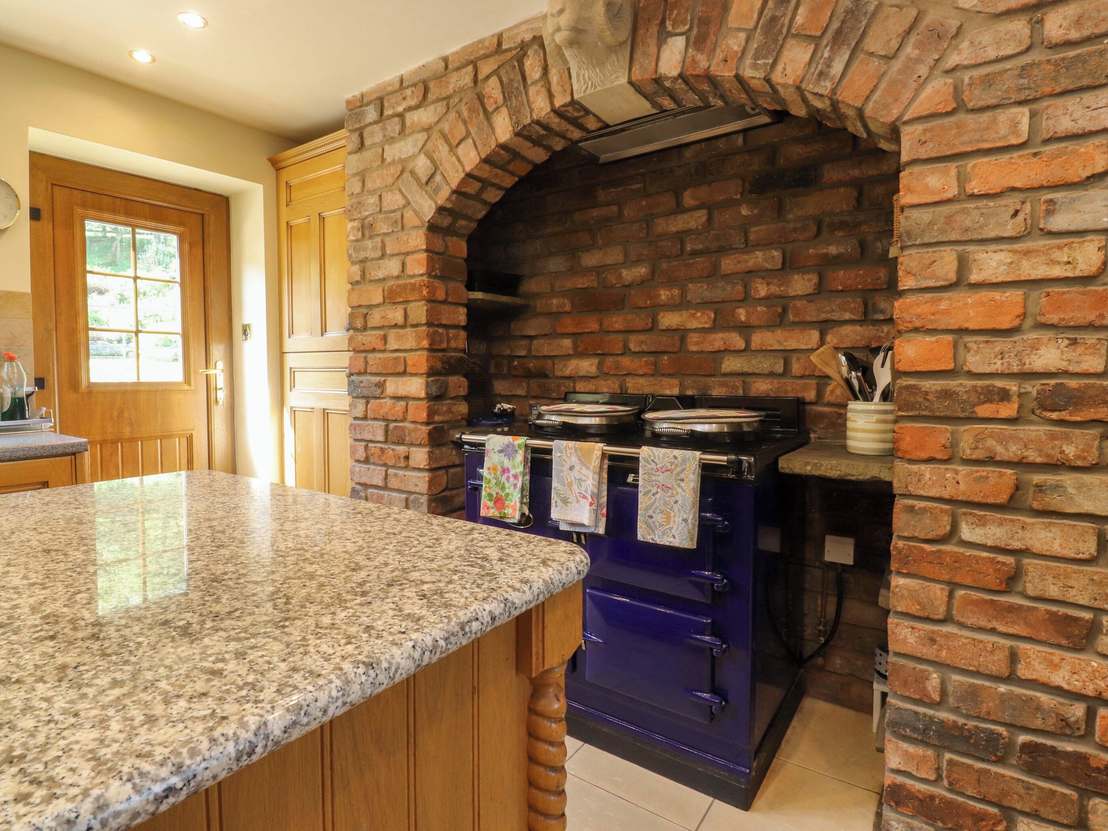 Cocina con arco de ladrillo, encimera de granito y estufa azul.
