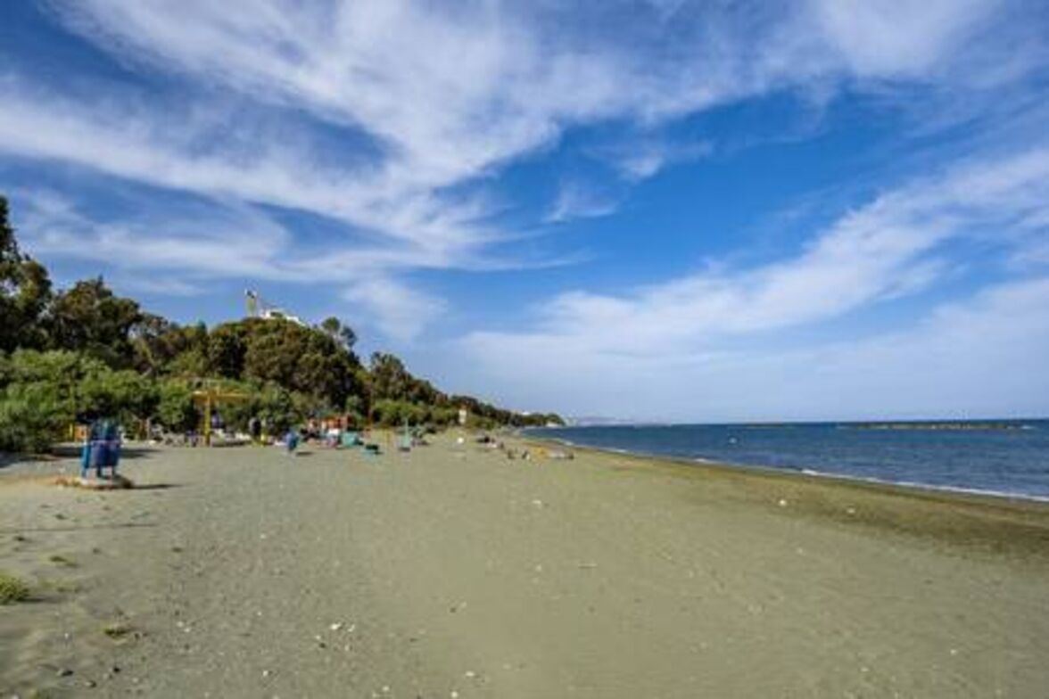 A beach with a clear sky, a few people, and a structure on the left.