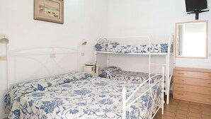 A room with bunk beds, a bedside table, a lamp, a framed picture on the wall, and a TV mounted on the wall. - Tower Hotels (Viareggio)