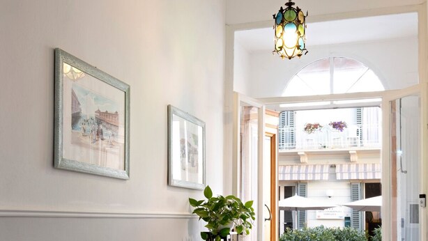 A hallway with two chairs, a hanging light fixture, and a potted plant. - Tower Hotels (Viareggio)