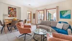 Uma sala de estar moderna com um sofá, poltronas, uma mesa de centro e um espaço de jantar com cadeiras e uma mesa.