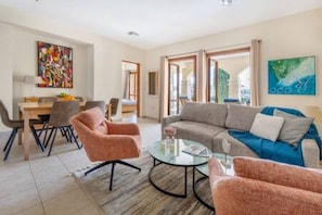 Ein modernes Wohnzimmer mit einer Couch, Sesseln, einem Couchtisch und einem Essbereich mit Stühlen und einem Tisch.