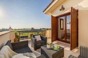 Ein Balkon mit Korbmöbeln, einer Schiebetür und Blick auf die Landschaft.
