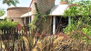 A building with cylindrical brick towers and a covered porch area. - Eco Hamlet Farmstay (Mawal)
