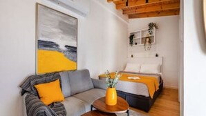 A modern room with a sofa, a small round table, a bed, and a painting on the wall. - Olga Apt 4 - lovely studio on ground floor (Limassol)
