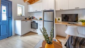 A compact kitchen with white cabinets, a built-in oven, a refrigerator, and a television on the counter. - Olga Apt 4 - lovely studio on ground floor (Limassol)