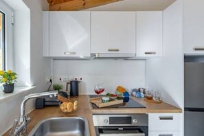 Une cuisine moderne avec des meubles blancs, un évier en acier inoxydable et un plan de travail en bois.