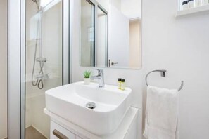 Une salle de bain moderne avec une douche à parois de verre, un lavabo blanc et un miroir.