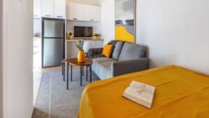 A compact living space with a bed, a sofa, a small table, and a kitchen area in the background. - Olga Apt 4 - lovely studio on ground floor (Limassol)