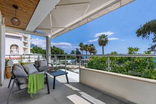 Un balcon avec vue sur les palmiers et un ciel dégagé.