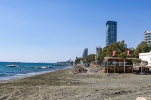 Une plage avec un bâtiment, un bateau et une structure ornée de drapeaux.