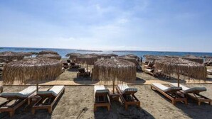 Ein Strand mit Liegestühlen und Reetdachschirmen.
