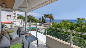 Ein Balkon mit Pool, Gartenmöbeln und Meerblick.