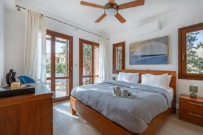 Een slaapkamer met een bed, een bureau, een stoel, een plafondventilator en een raam met uitzicht.