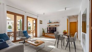 A modern living room with a sofa, coffee table, and dining area with chairs. - BK02 Adjacent to Aphrodite Hills – Pool & Sea View (Kouklia)