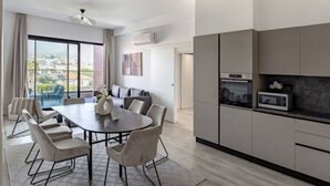 Cozinha moderna com micro-ondas, área de jantar com mesa e cadeiras, e uma janela grande com vista.