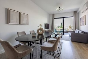 A modern living room with a round table, chairs, a sofa, and a TV.