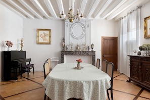 A dining room with a table, chairs, a chandelier, a fireplace, and a television.