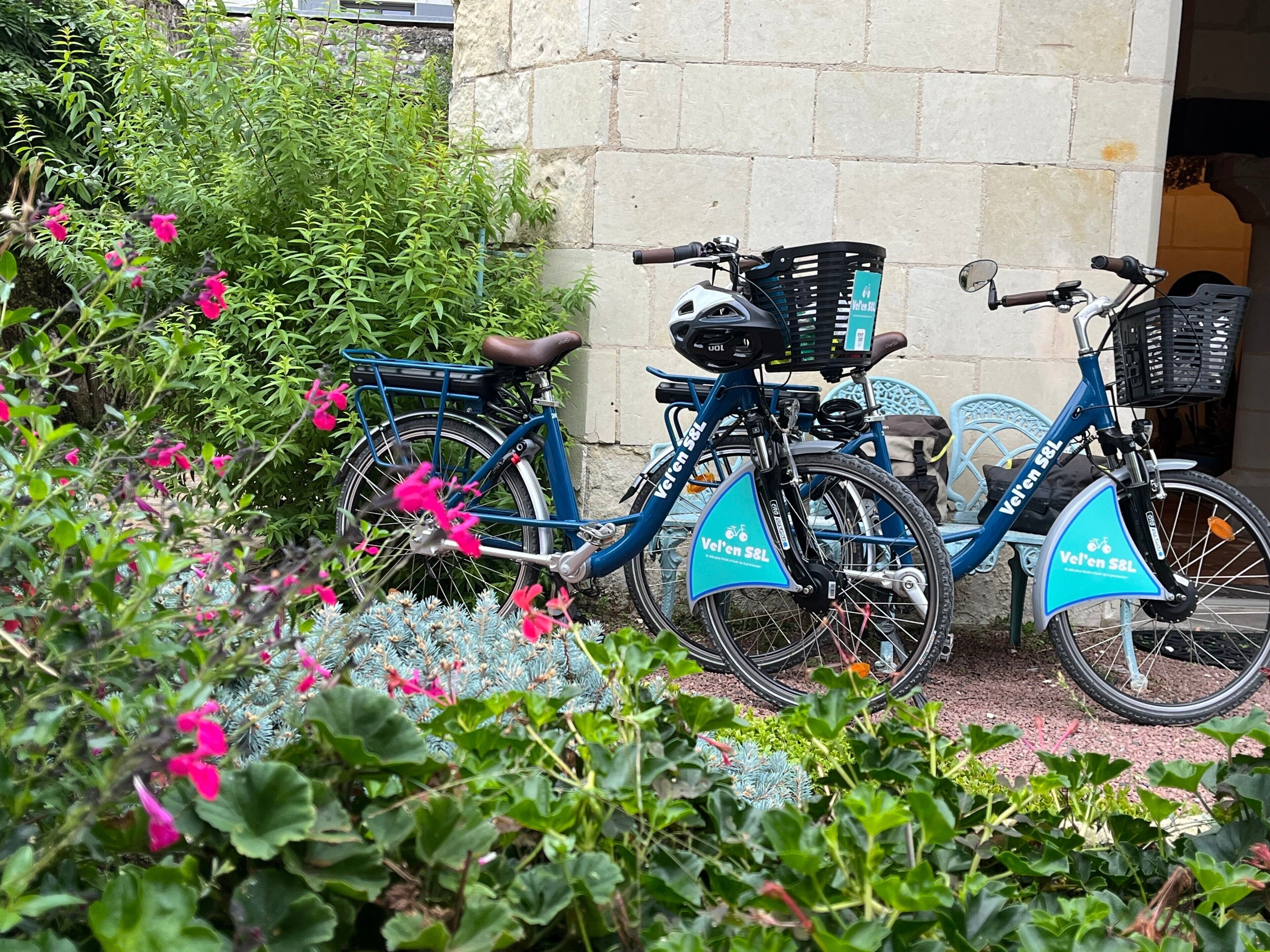 Deux vélos sont garés contre un mur de pierre, l’un d’eux est équipé d’un panier et d’un siège.