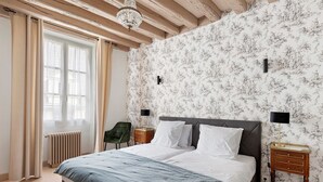 A bedroom with a large bed, a radiator, a green chair, and a nightstand with a lamp.