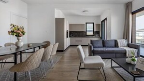 Ett modernt hotellrum med en matplats, en soffa och utsikt över staden.