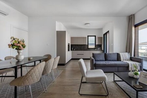 Une chambre d’hôtel moderne avec un coin repas, un canapé et une vue sur la ville.