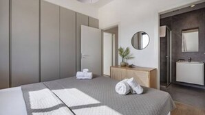 Ett modernt hotellrum med en säng, ett sängbord, en spegel och en garderob.