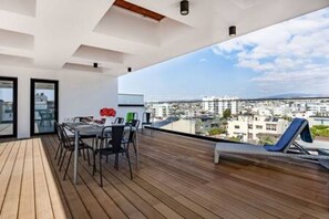Een balkon met een eettafel en stoelen, een lounge stoel, en uitzicht over de stad.