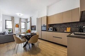 Een moderne keuken met een eethoek, houten vloeren en lichte kastjes.