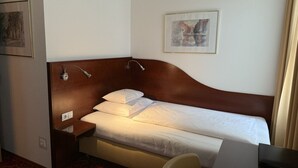 A hotel room with a single bed, a bedside table, a chair, a desk, and a framed picture on the wall. - Hotel Jäger Single Room with Balcony (Wien)