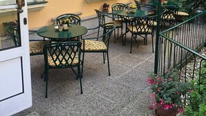 An outdoor patio with tables and chairs, a door, and a railing. - Hotel Jäger Single Room with Balcony (Wien)